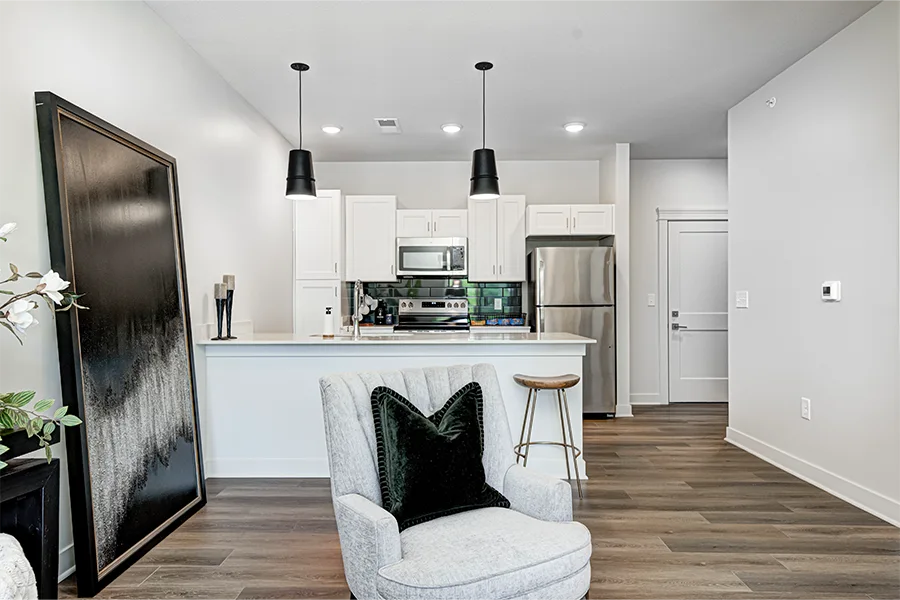 If you tour a staged apartment like this one at East Bank Apartments, ask if it's identical to the unit you'd be renting or if there are significant differences. An apartment living room and kitchen at East Bank Noblesville Riverside Apartments