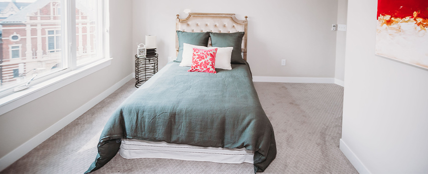 White bedroom with double windows on the left. Located at Penrose on Mass Apartments.